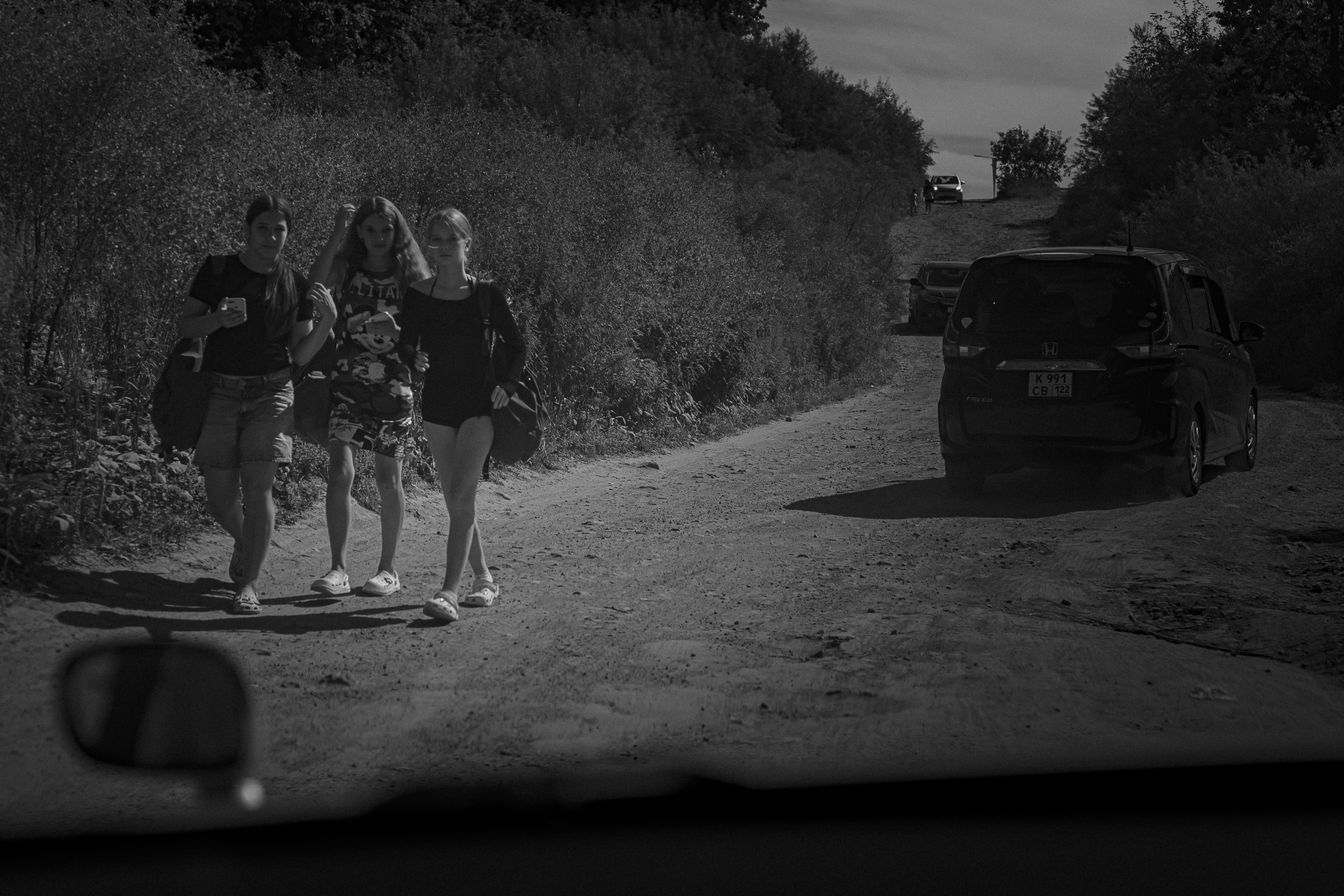 Three young women walk down a dirt road.