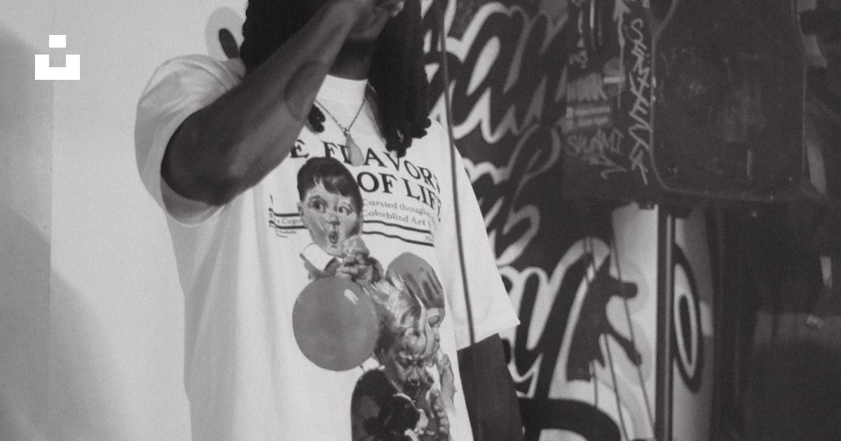 A man rapping into a microphone with graffiti in background photo ...