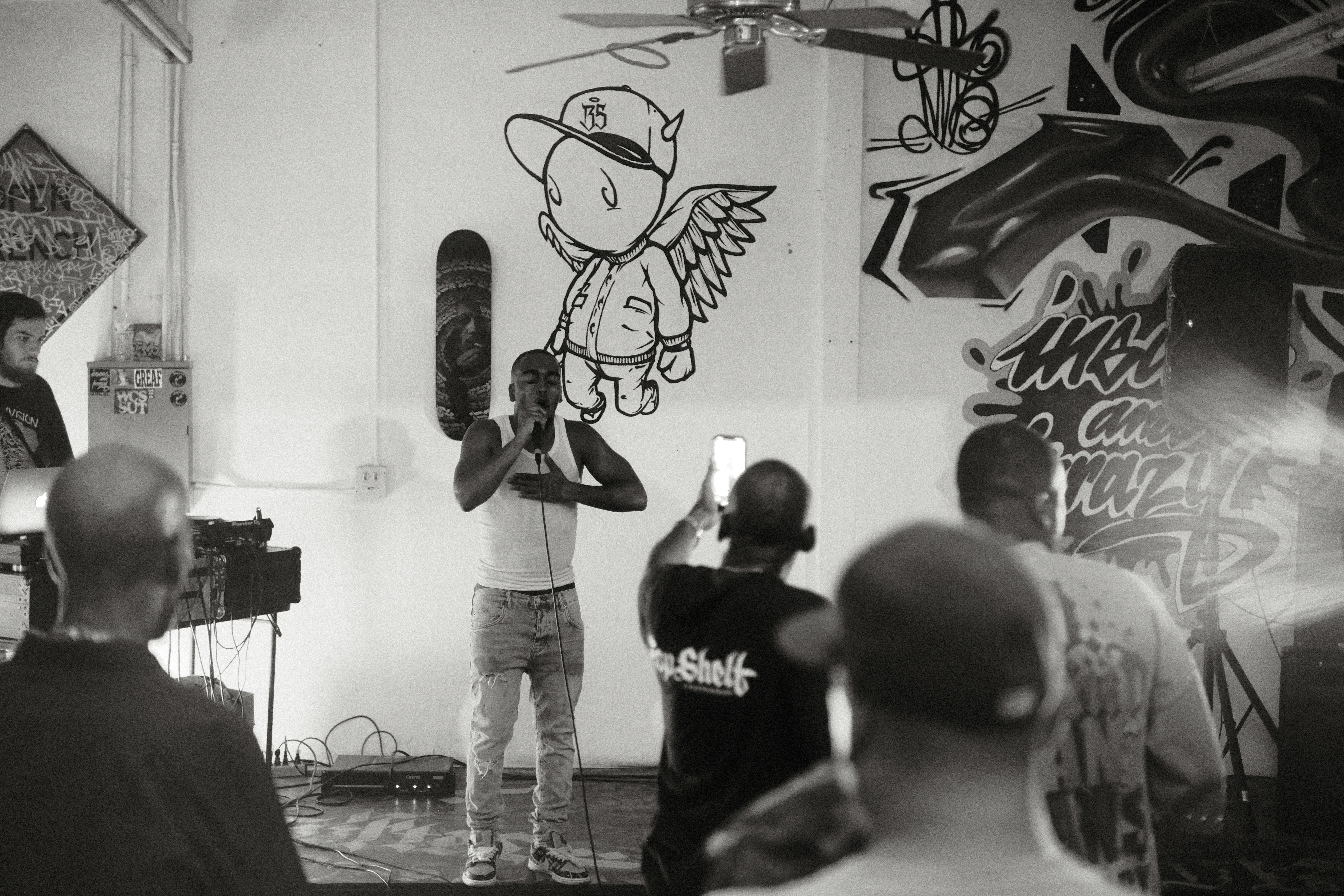 Rapper performs for an audience in a graffiti-covered room. photo ...
