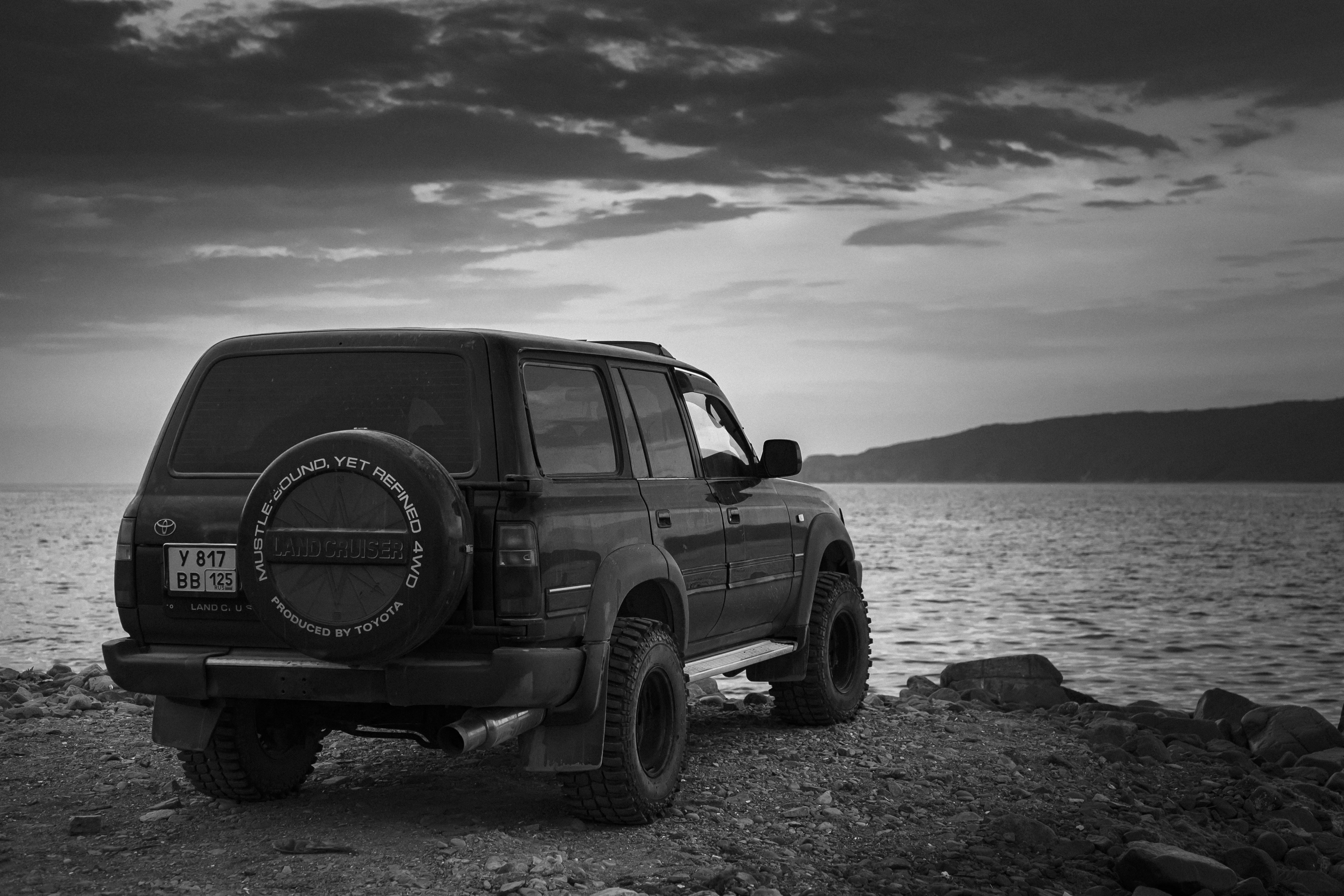 Black suv parked by the ocean at dusk.