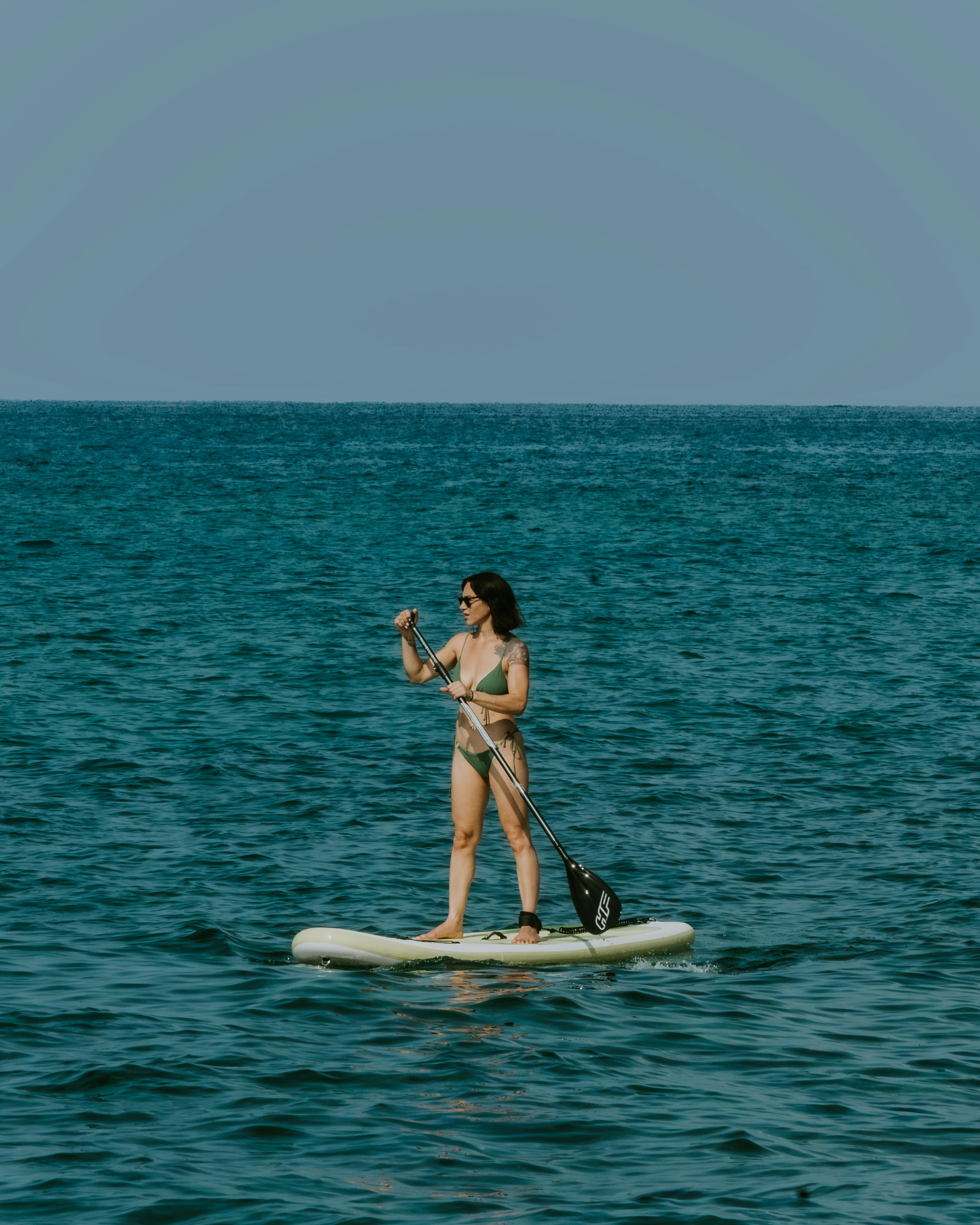 Woman paddleboarding on calm blue ocean water