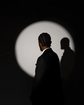 Man in suit illuminated by spotlight with shadow