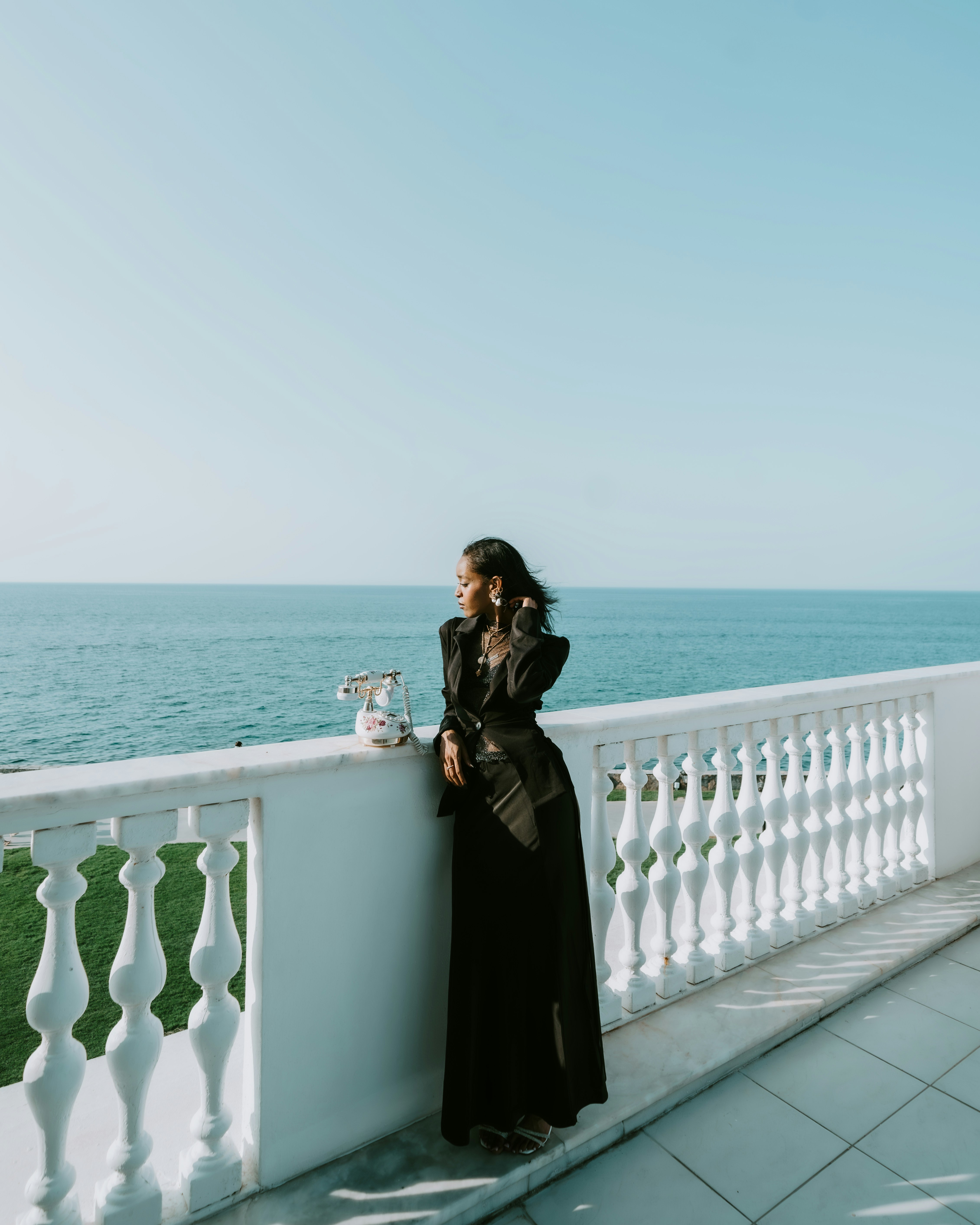Woman in black dress on balcony overlooking ocean