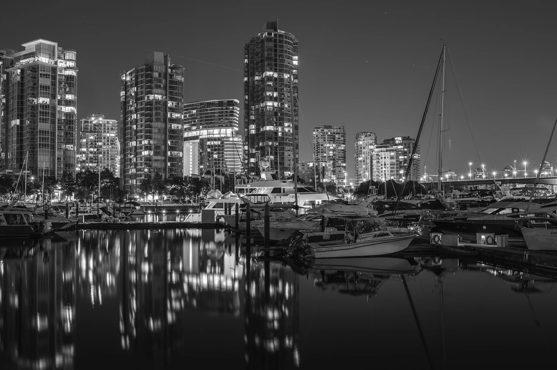 City skyline with boats docked at marina at night