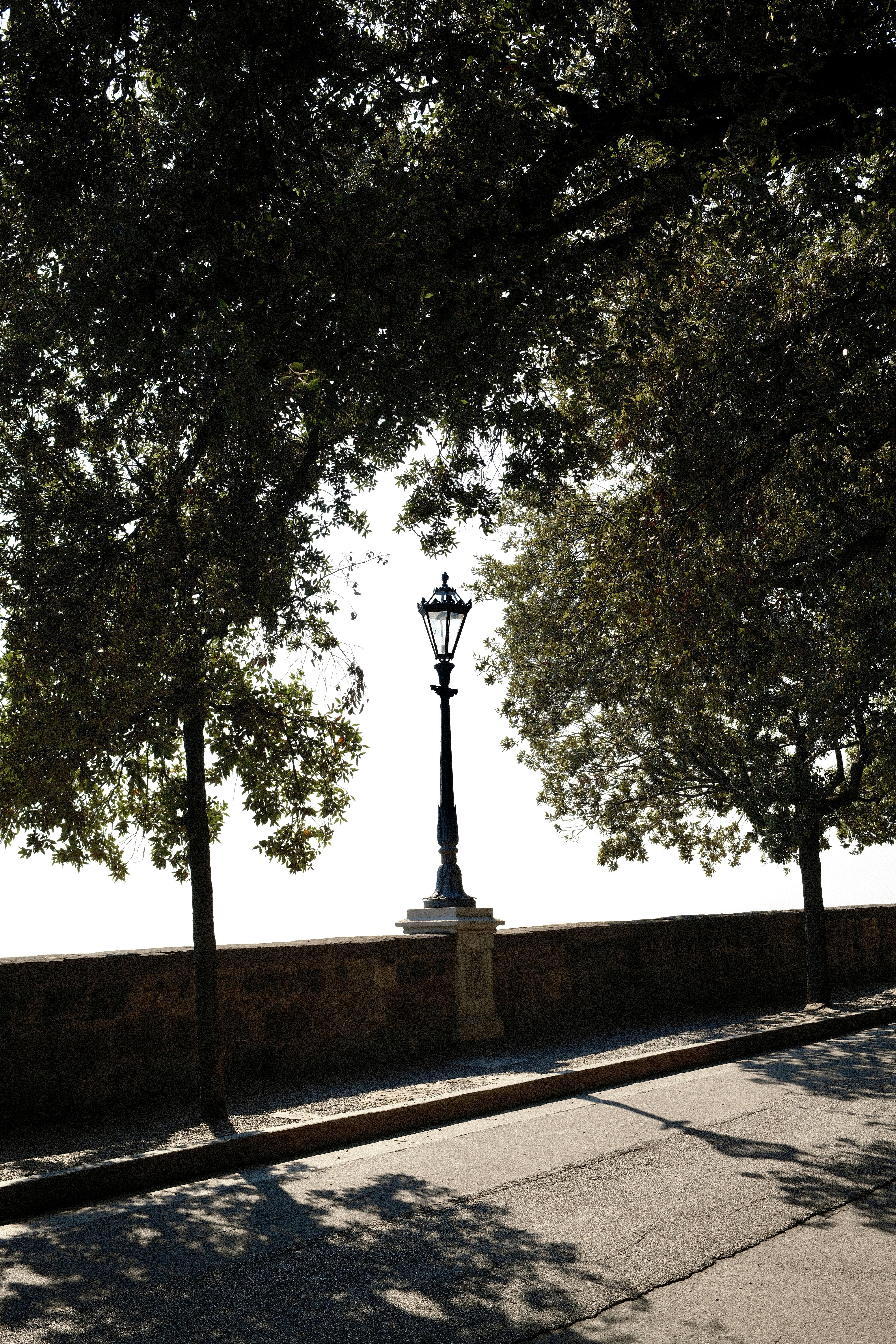 An old-fashioned lamppost stands behind a stone wall.
