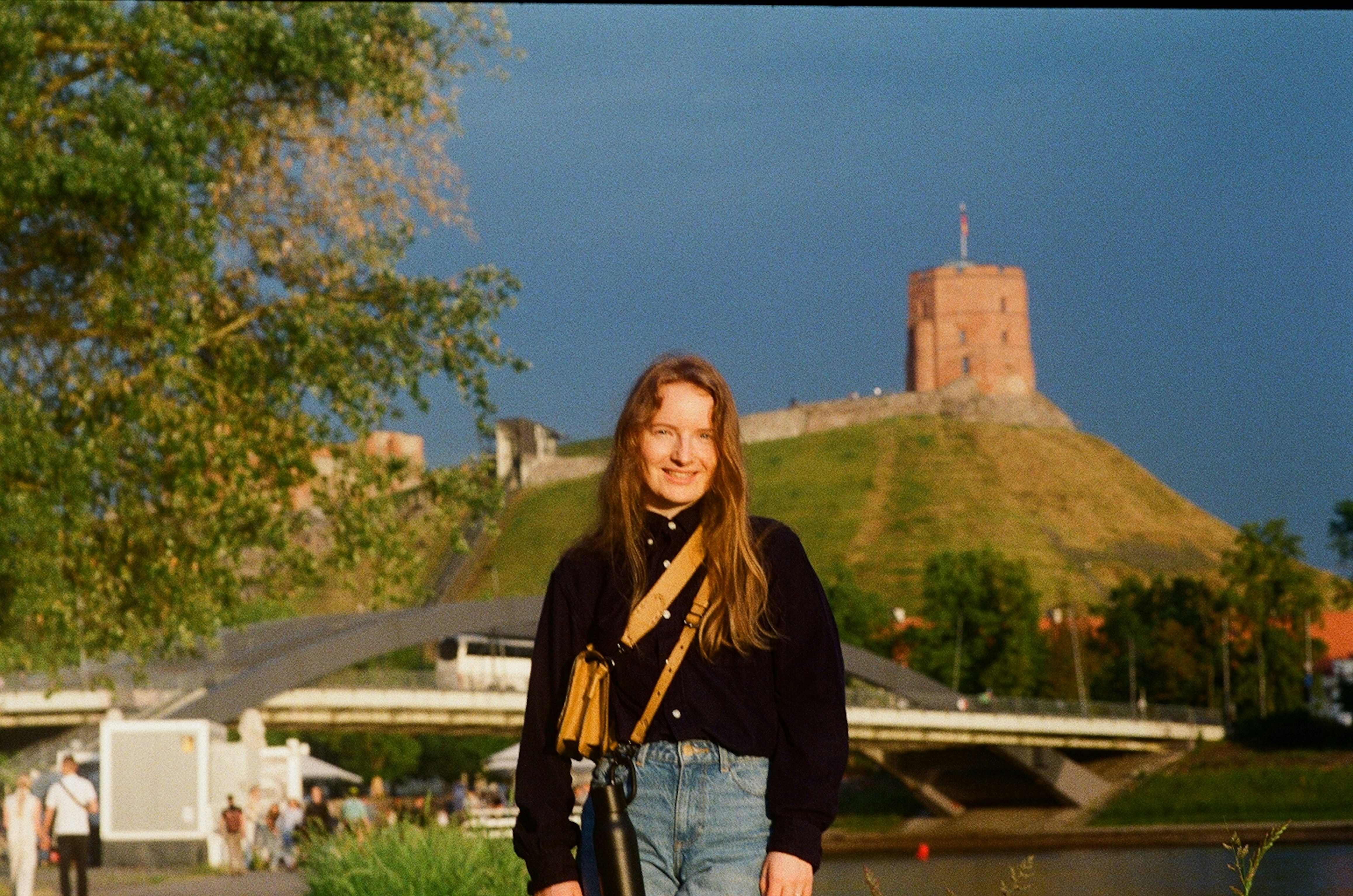 Woman standing with castle on hill behind her