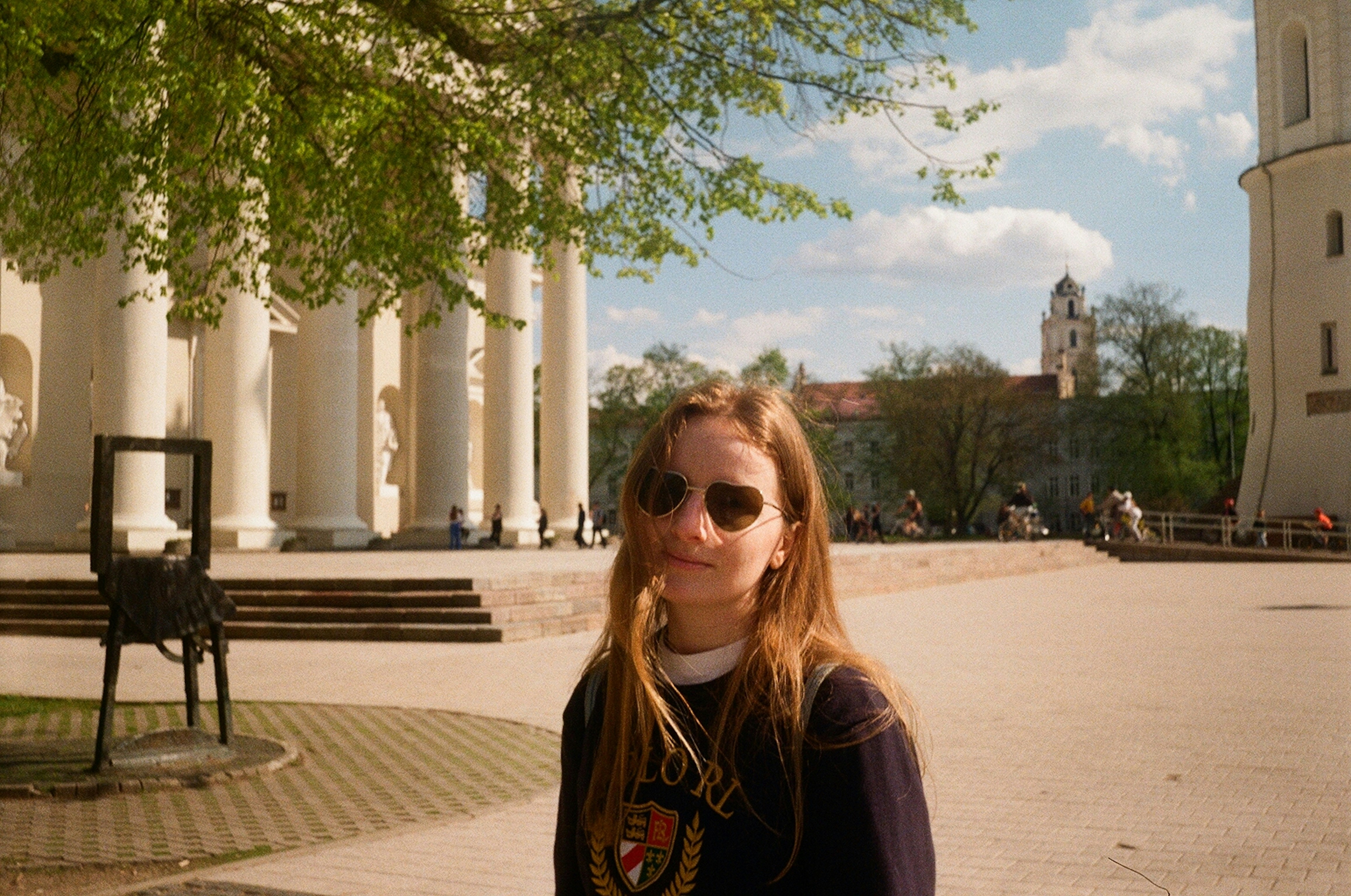 Young woman in sunglasses in front of white columns.