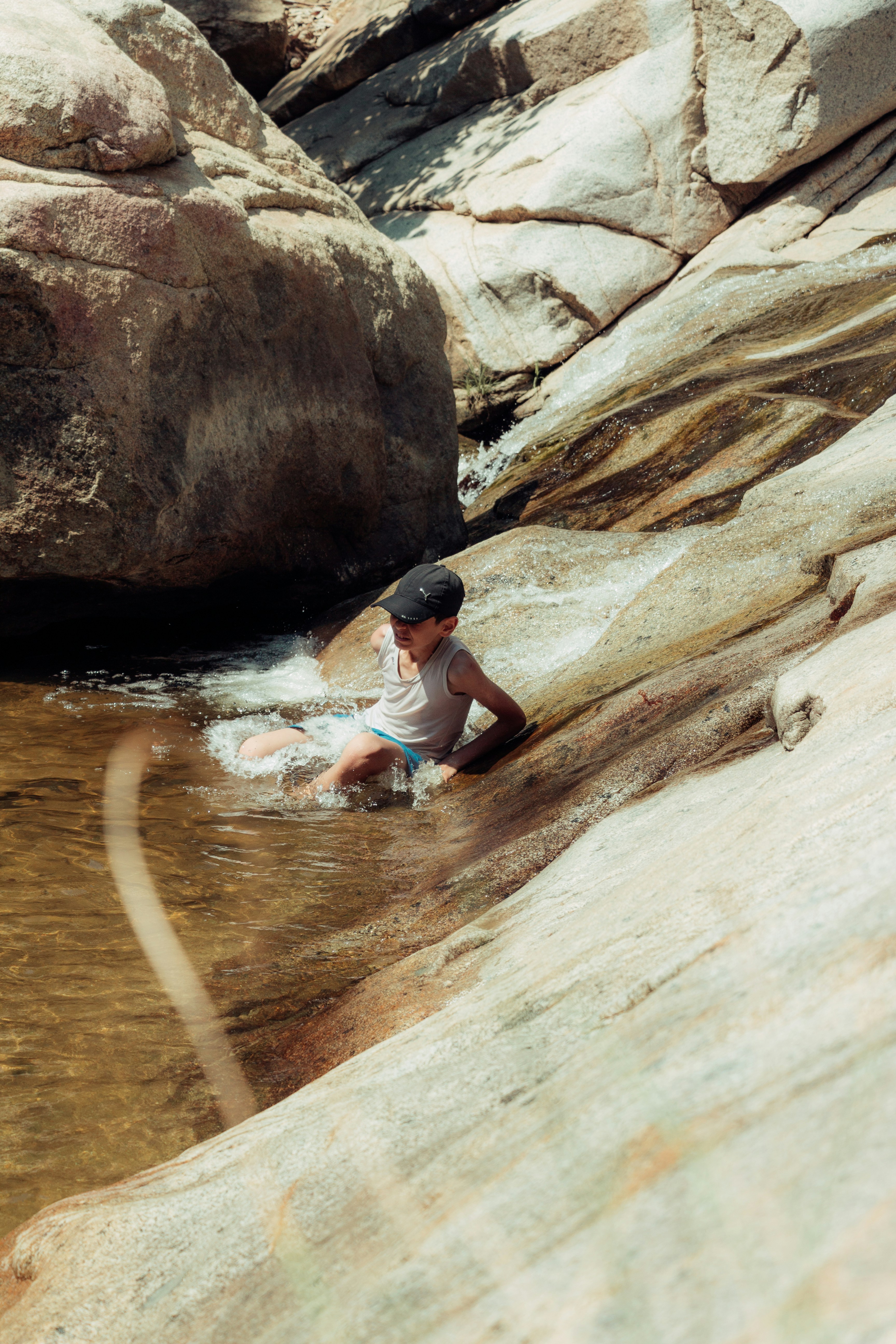 Child sliding down a rocky natural water slide