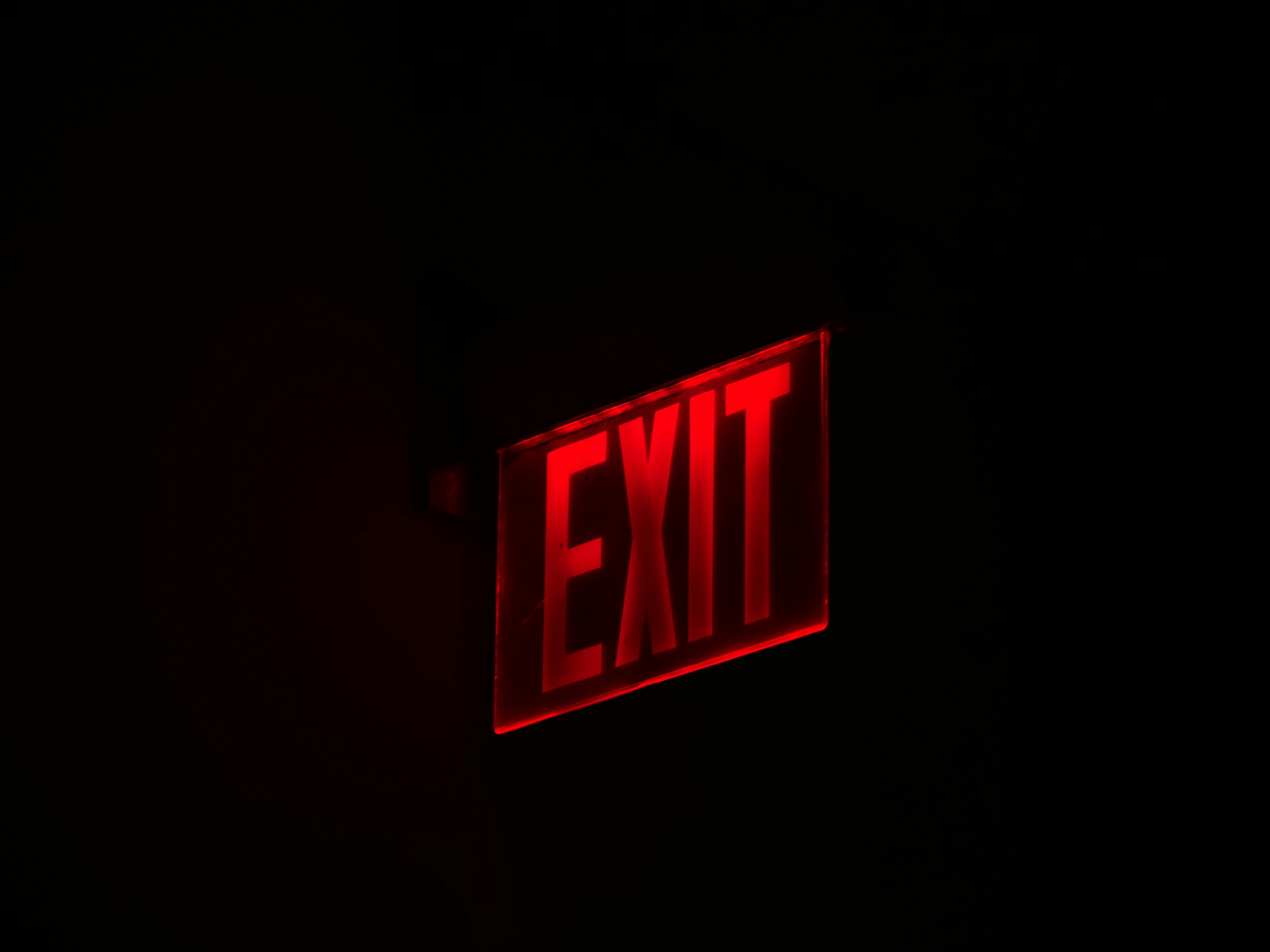 Red exit sign glowing in darkness