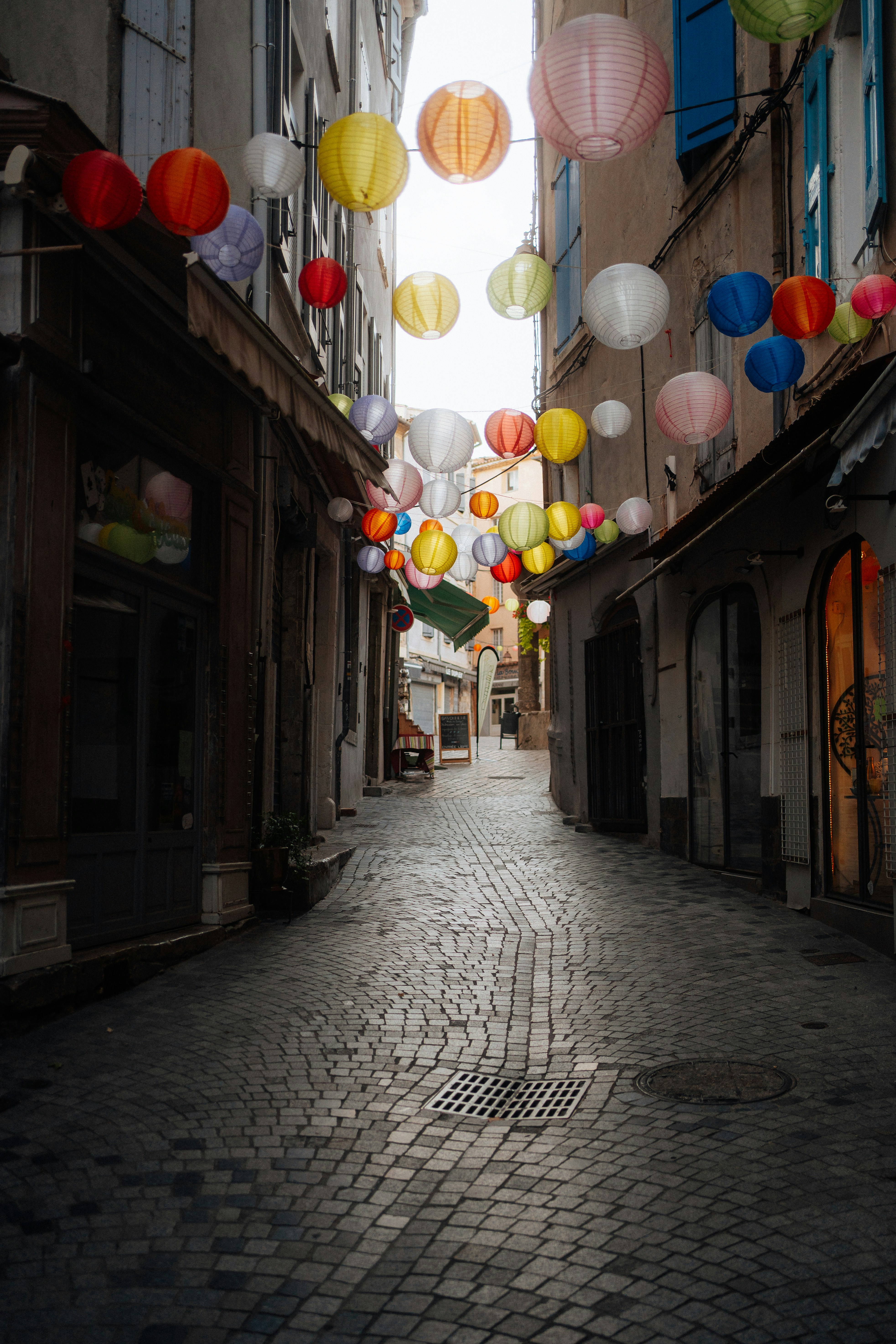 Colorful lanterns strung across a cobblestone alleyway