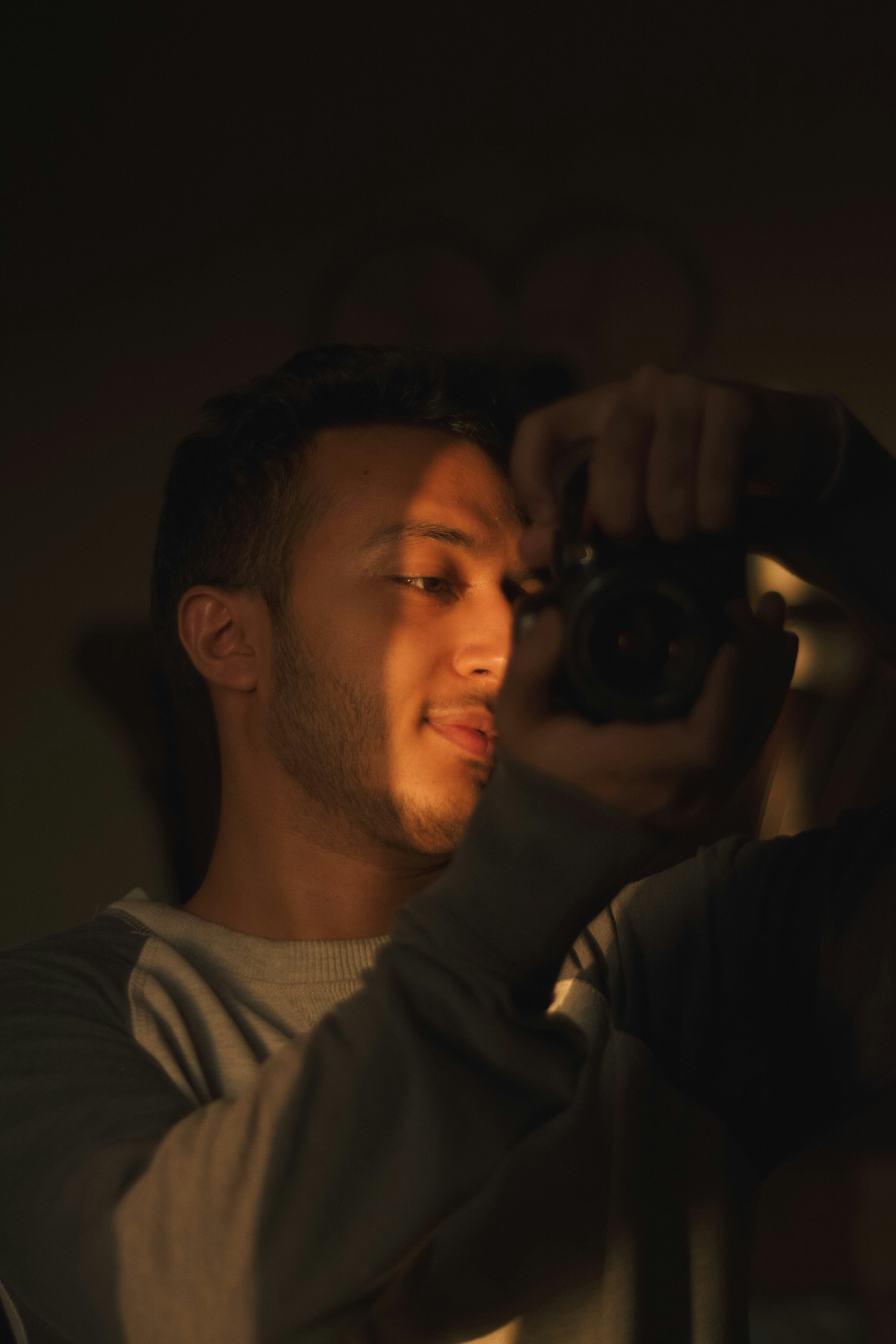 Man holding camera, illuminated by side light.