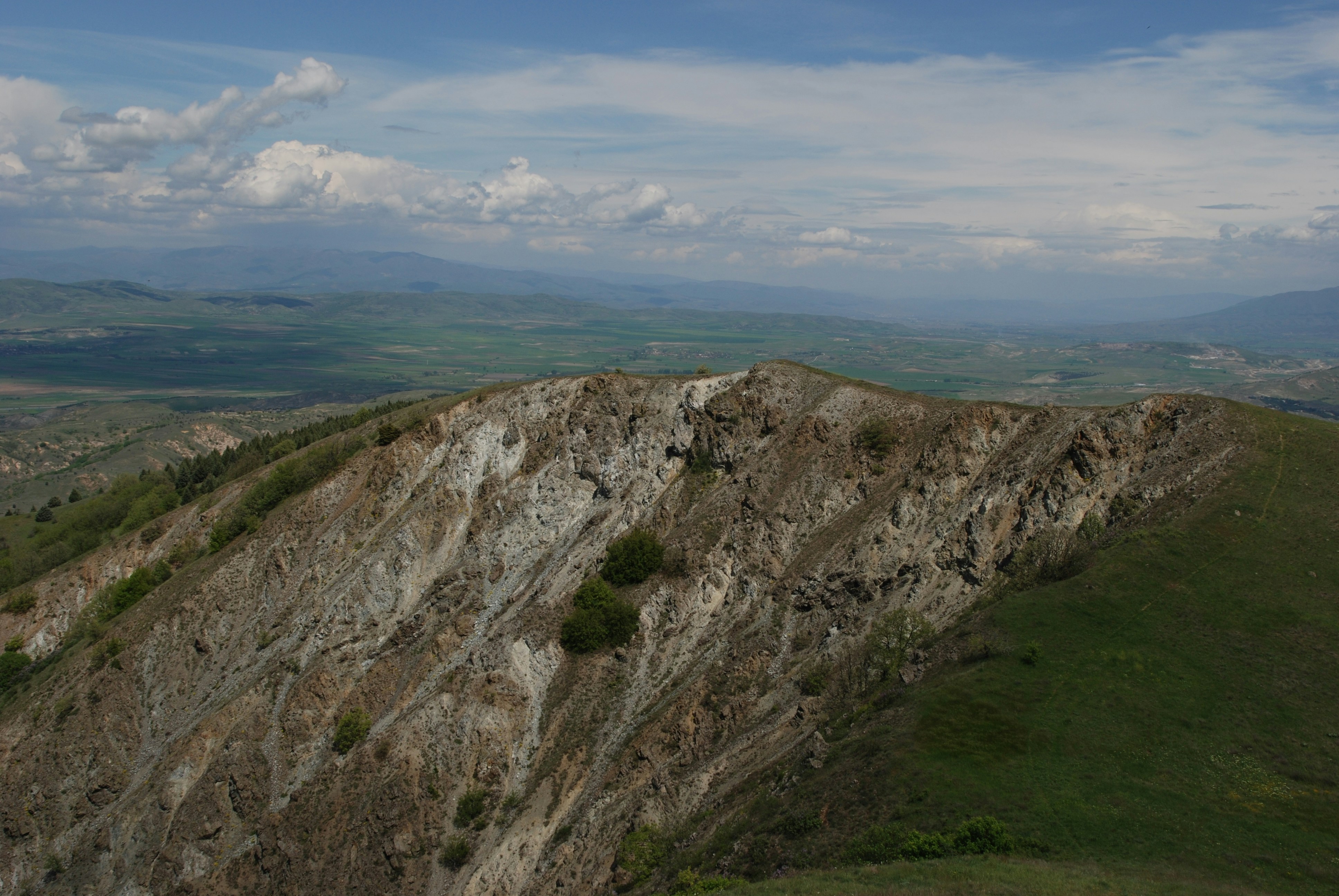 Cresta rocosa de las montañas con colinas verdes y cielo