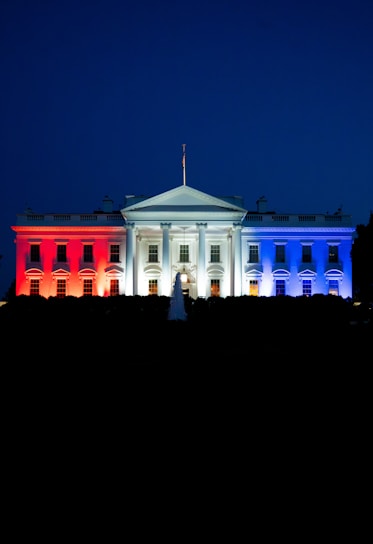 The white house illuminated with red, white, and blue lights.