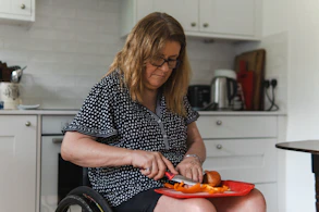 Woman in wheelchair preparing food in kitchen.