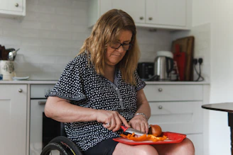 Woman in wheelchair preparing food in kitchen.