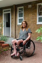 Woman in wheelchair smiling outdoors near brick building