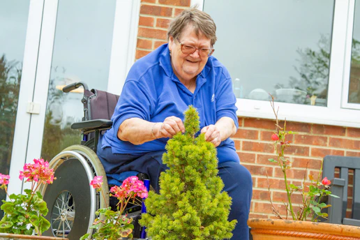 Elderly woman in wheelchair tending to small plant