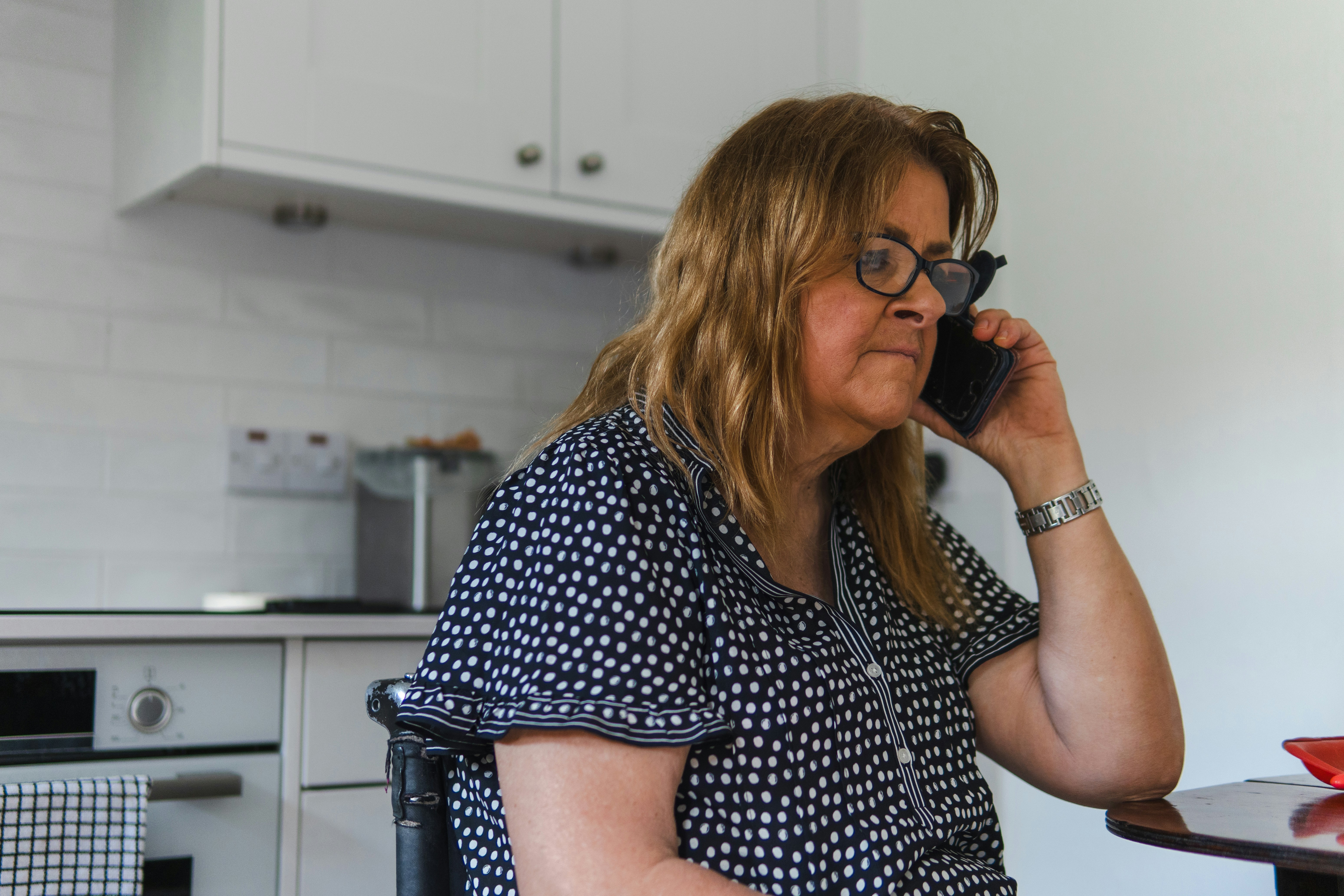 Woman talking on a mobile phone in a kitchen.