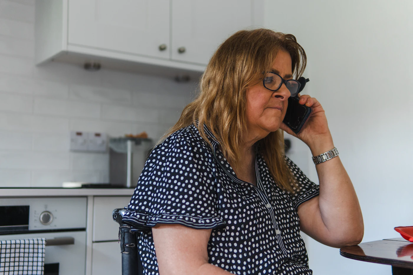 A woman talking on the phone in her kitchen