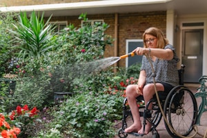 Woman in wheelchair waters plants in garden.