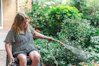 Woman in wheelchair waters plants with hose