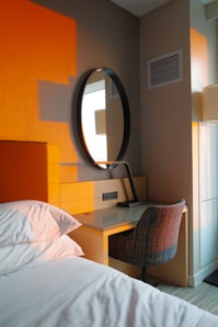 Bedroom corner with desk, mirror, and bed.