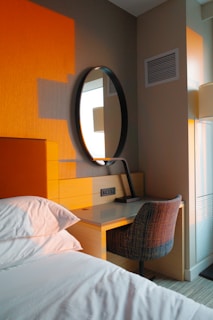 Bedroom corner with desk, mirror, and bed.