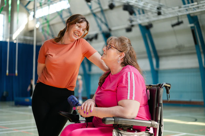 A support worker with a woman using a wheelchair in a gymnasium