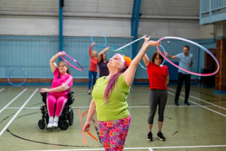 People of varying abilities practicing hula hooping indoors.