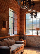Sofa in a room with exposed brick and large windows.