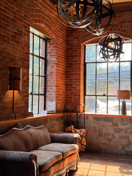 Sofa in a room with exposed brick and large windows.