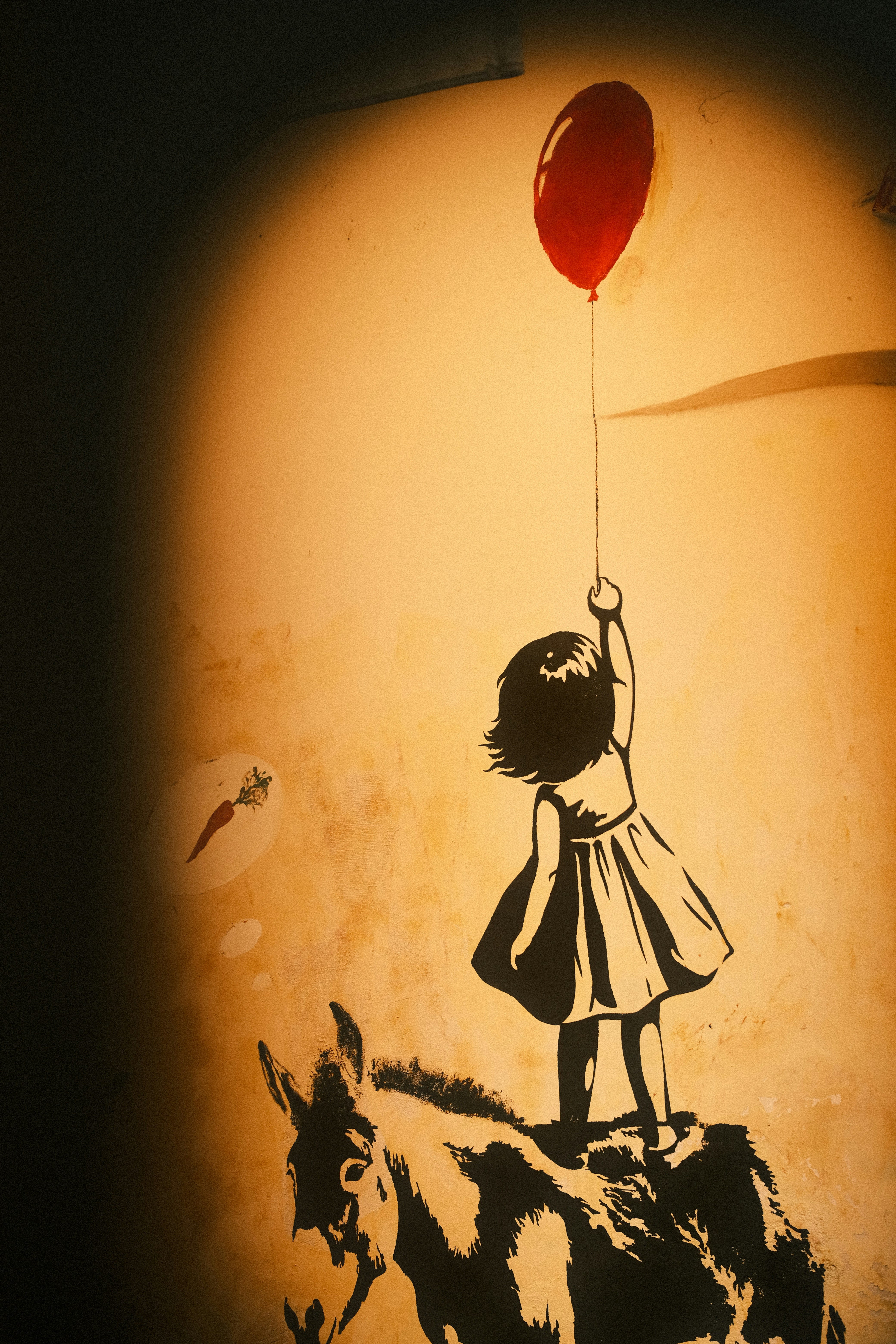 Girl holding red balloon on donkey