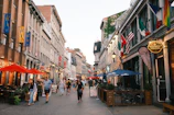 People stroll down a european-style street with shops.