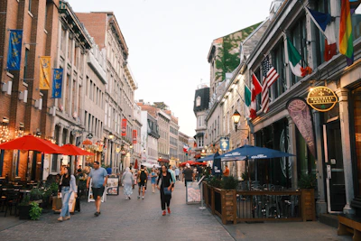 People stroll down a european-style street with shops.