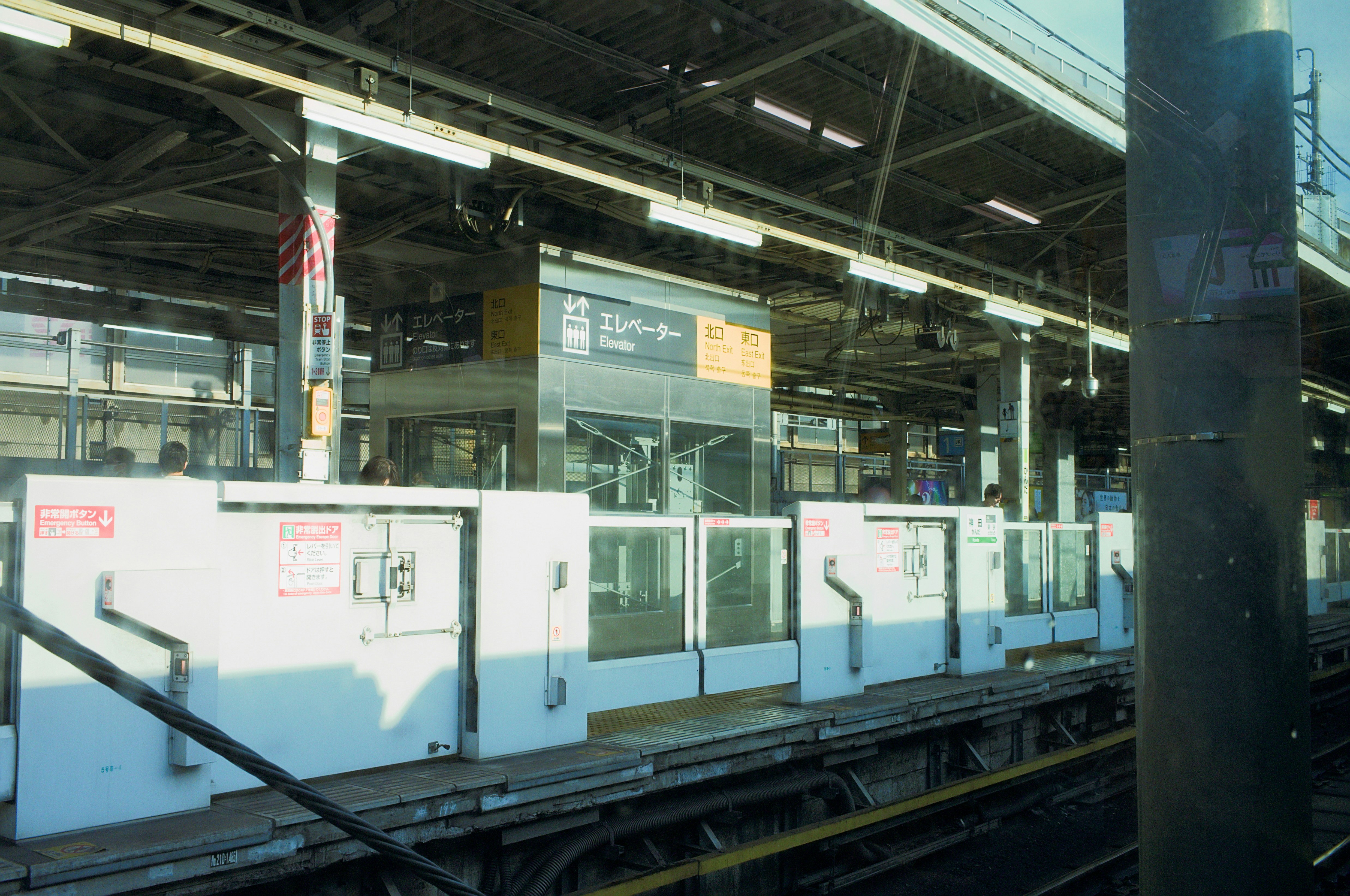 Plataforma de la estación de tren con barreras y vías blancas.