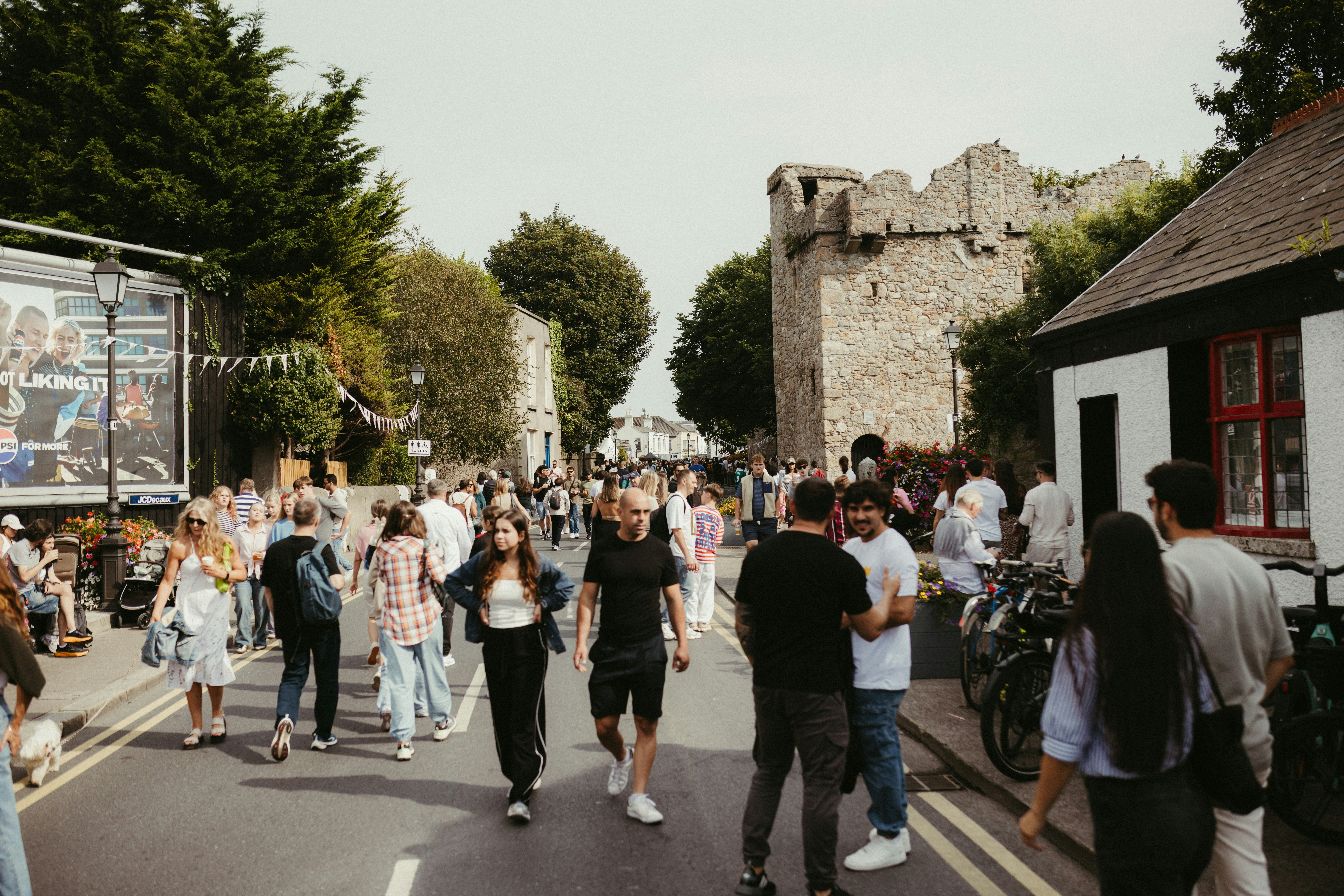 People walking down a street with buildings and trees.