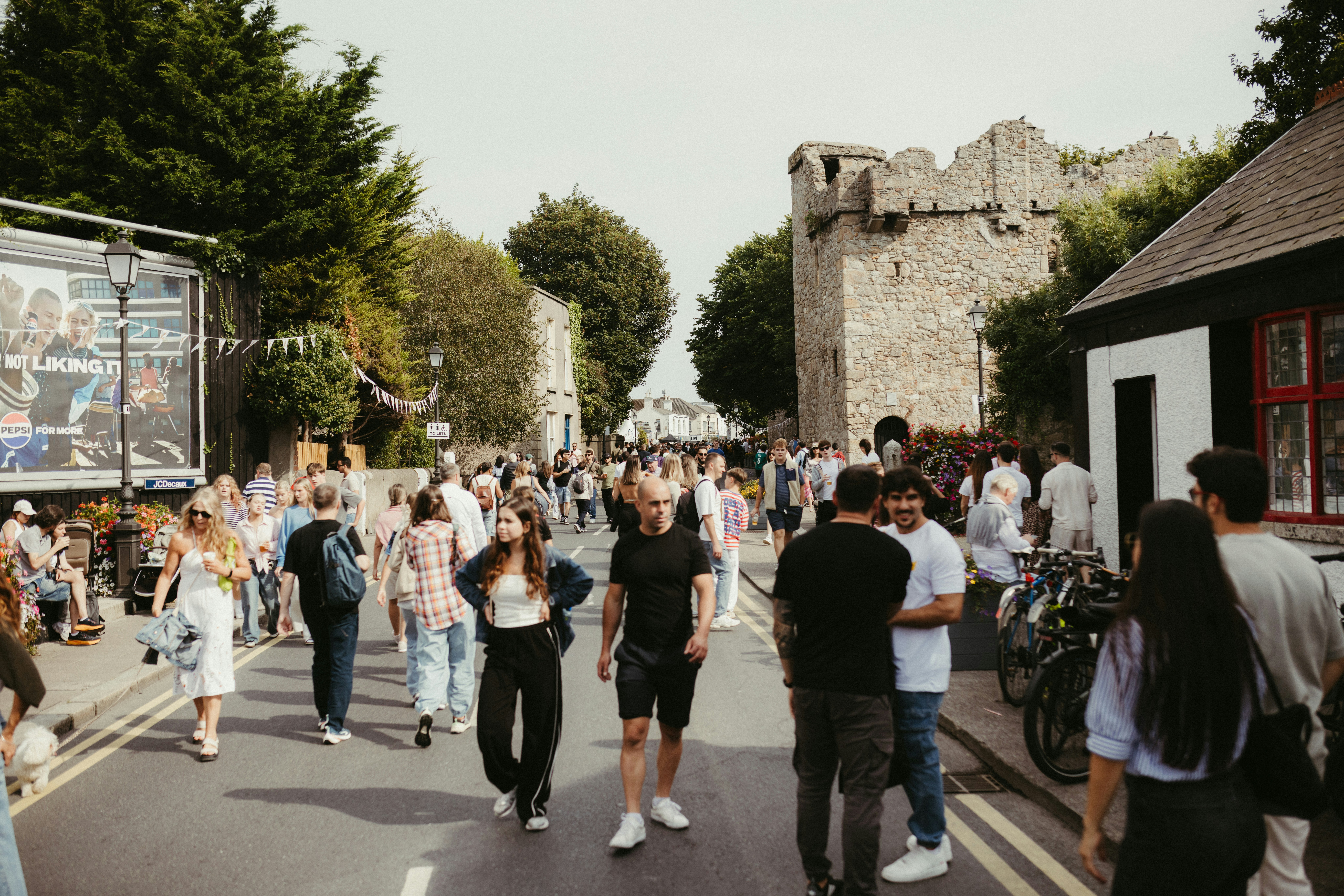 Crowd of people walking down a street with buildings.