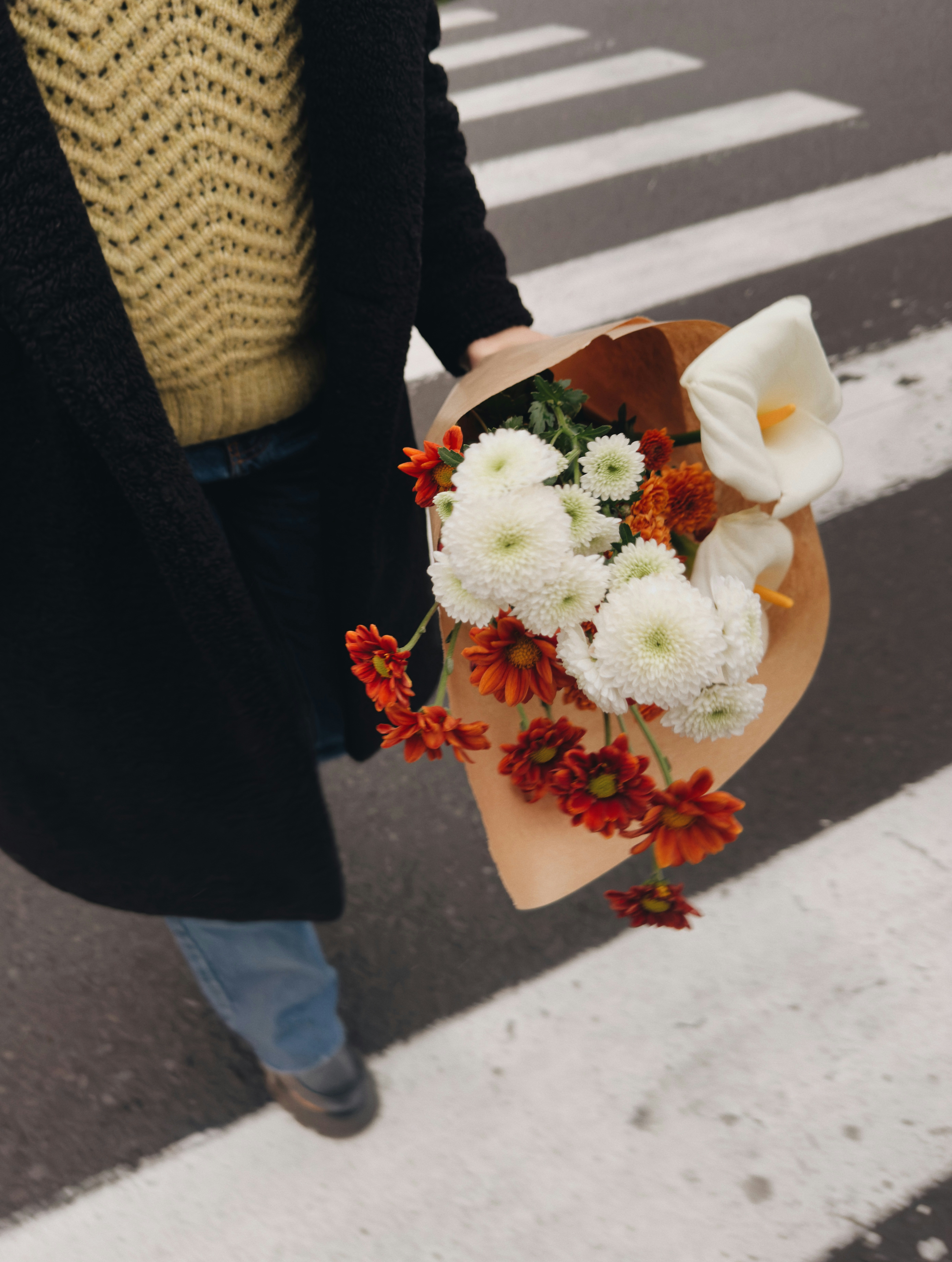 Person holding a bouquet of flowers on a crosswalk