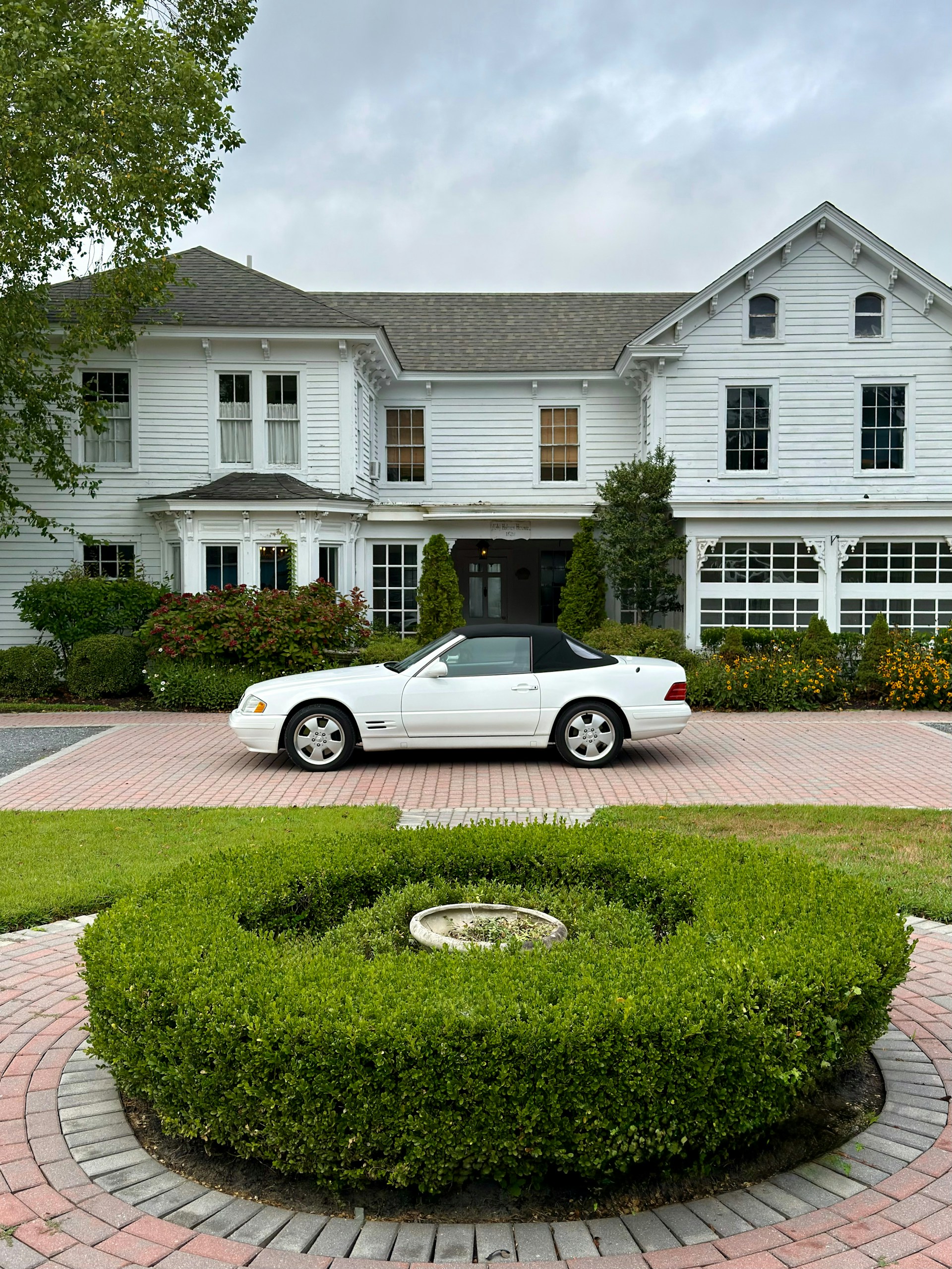 White convertible parked in front of a large white house.