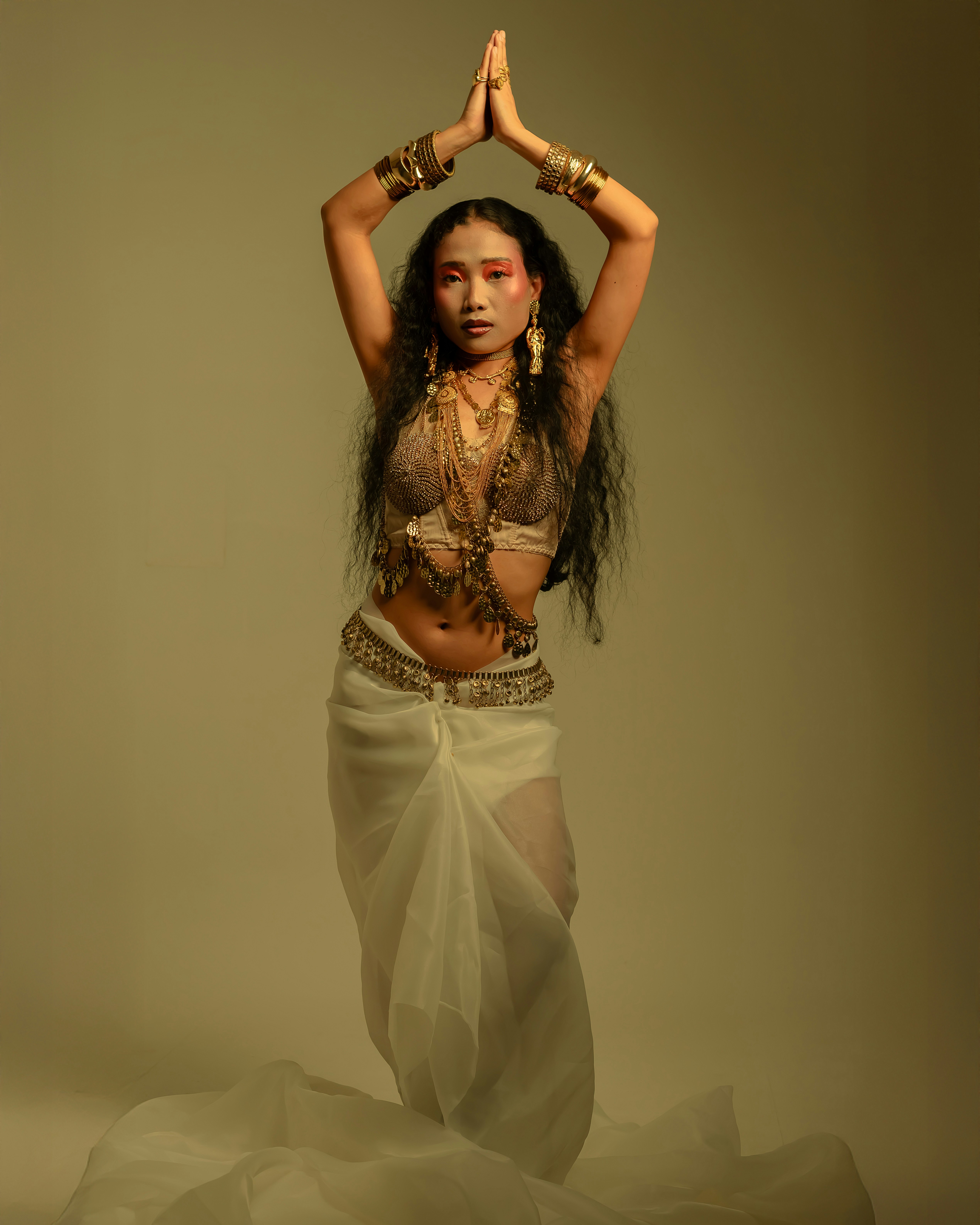 Woman in traditional attire with hands clasped overhead