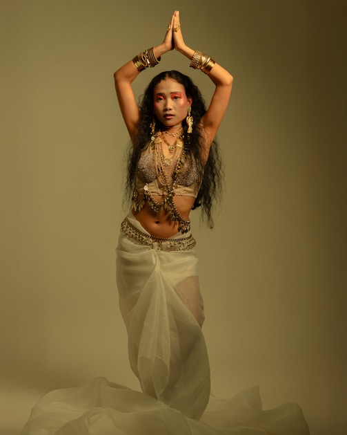 Woman in traditional attire with hands clasped overhead