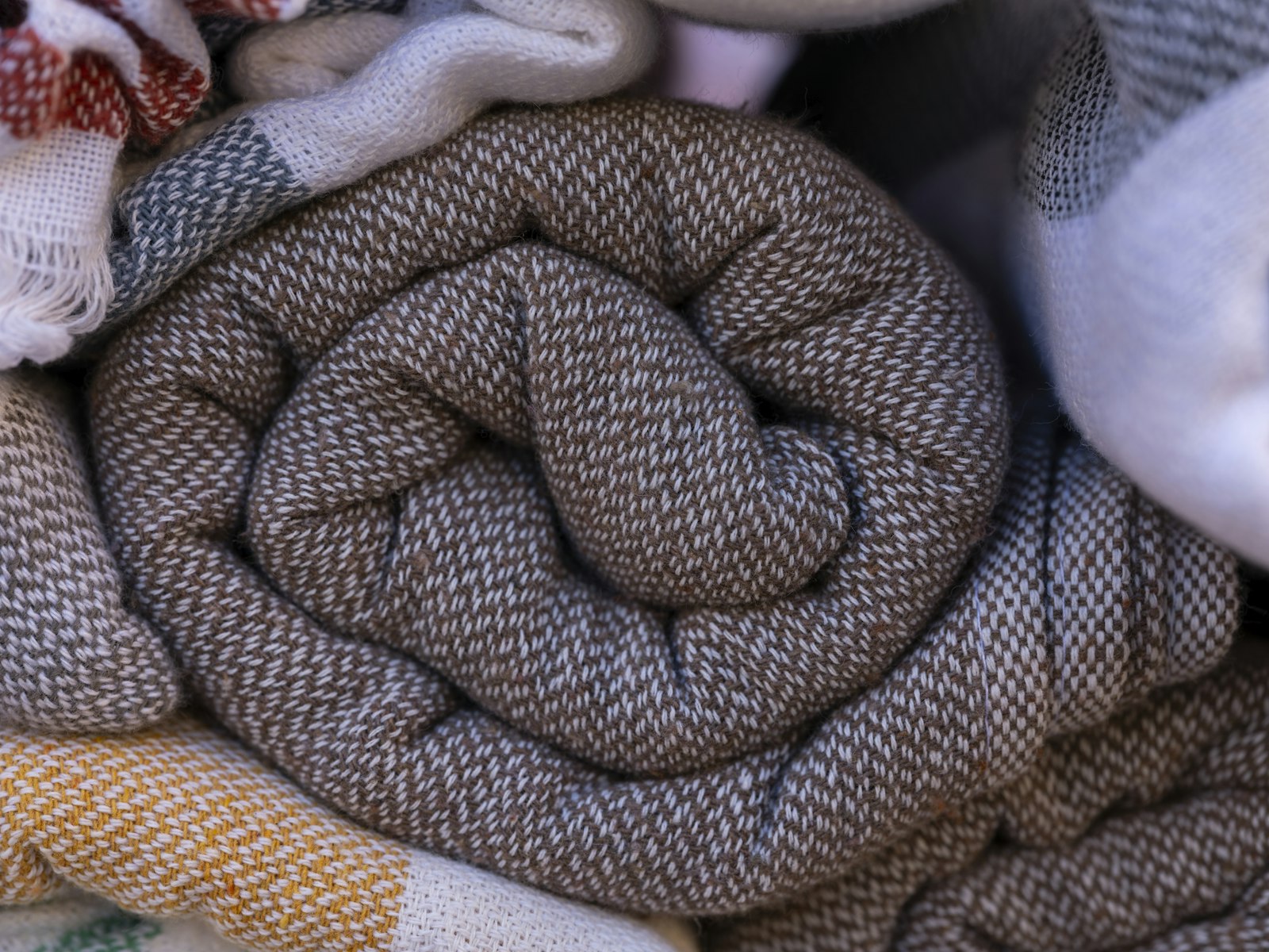 Des plaids en laine roulés, un brun chiné au premier plan