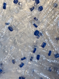 A pile of empty plastic water bottles with blue caps
