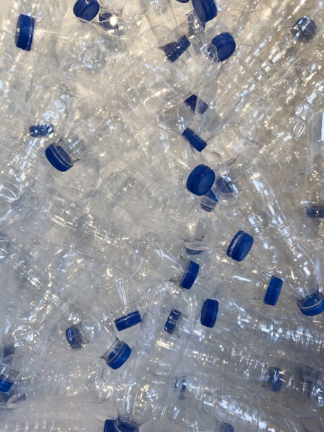 A pile of empty plastic water bottles with blue caps