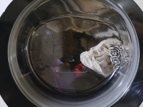 Tambor de lavadora en ciclo de lavado con agua y ropa