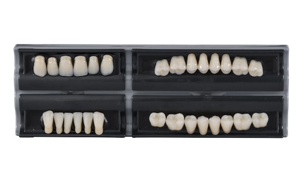 Four sets of artificial teeth in black cases.