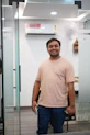 A man smiling while standing in an office doorway.