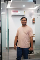A man smiling while standing in an office doorway.