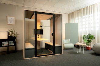 Modern office meeting pod with seating and desk.