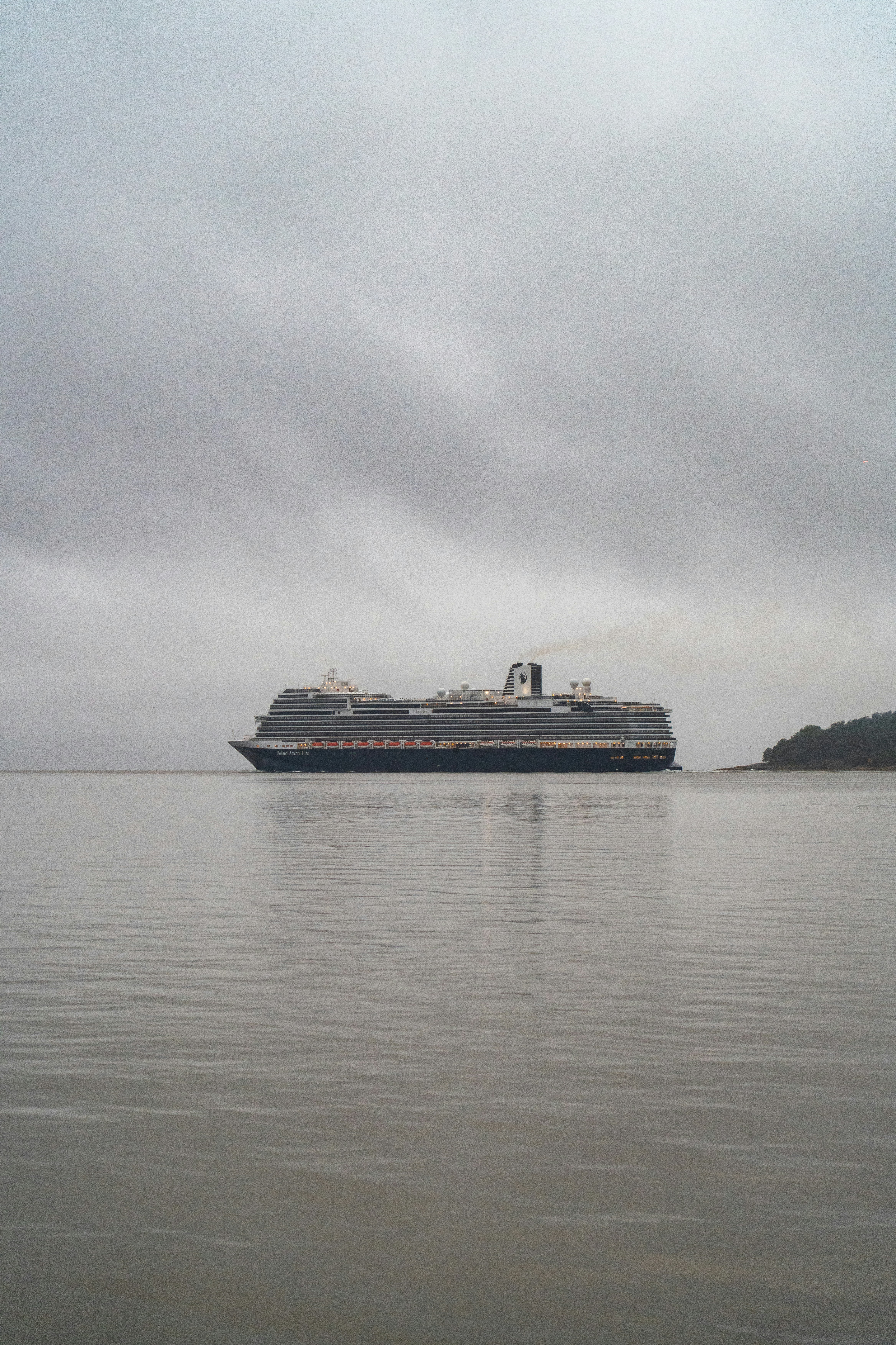 Large cruise ship sailing on calm water under cloudy sky.